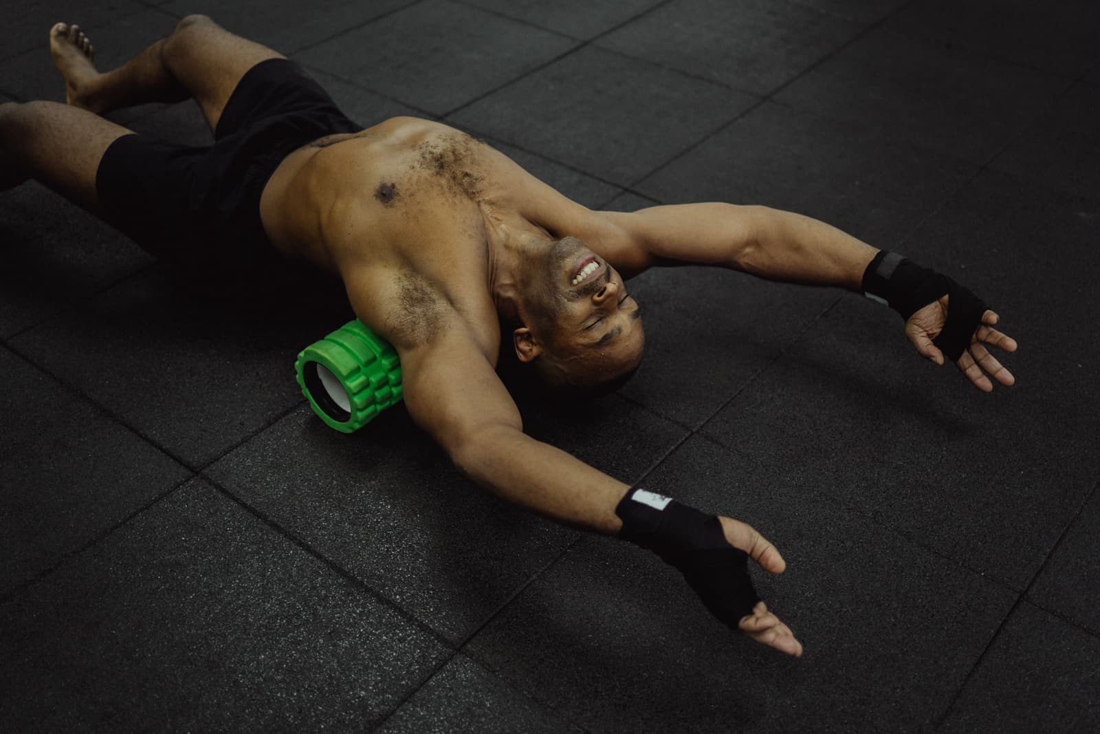 An athlete rolling a calf on a foam roller on a gym floor